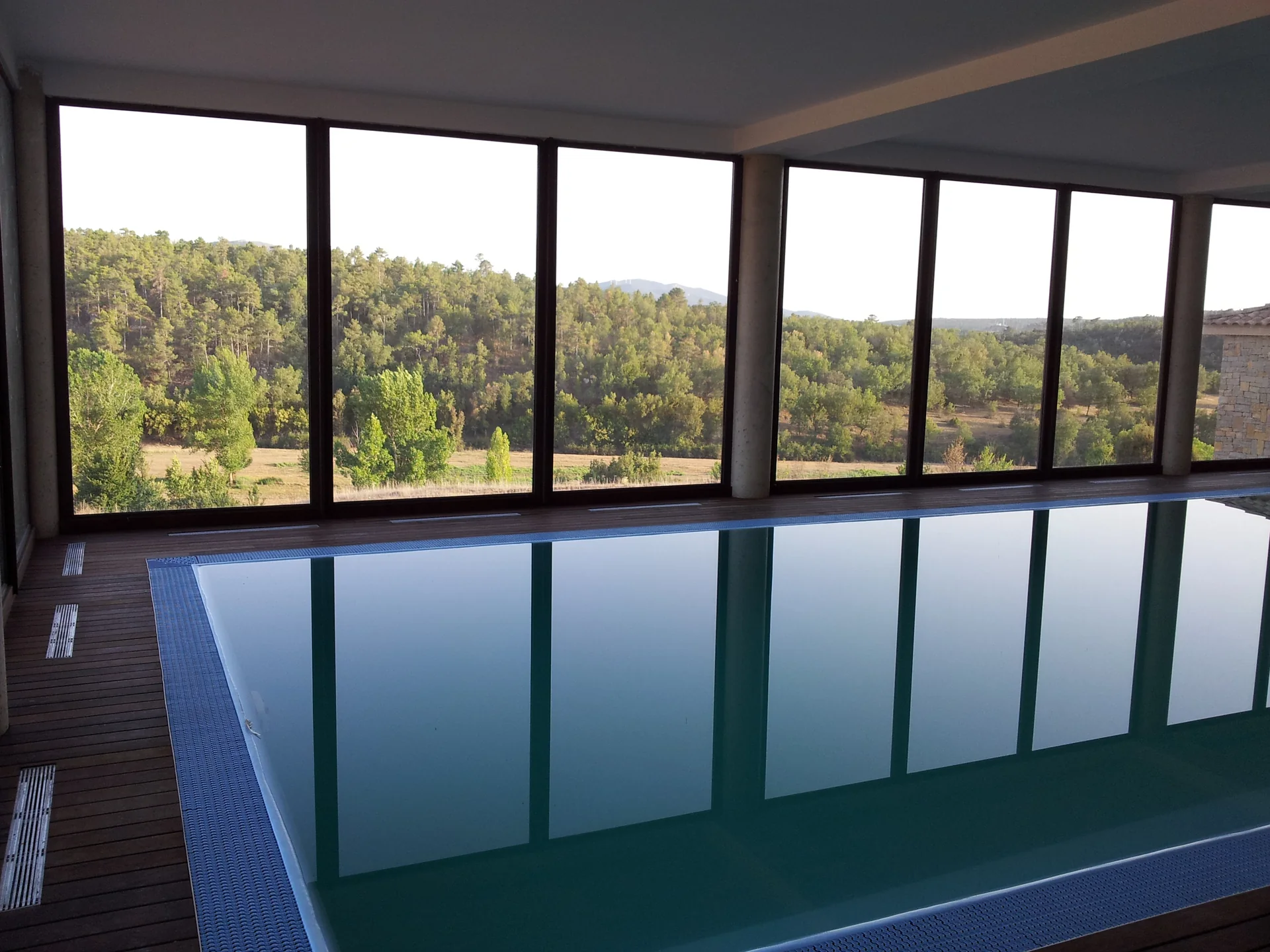 Piscina interior junto al cerramiento acristalado